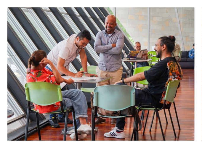Grupo de personas reunidas en una mesa, uno de ellos está escribiendo en una papel