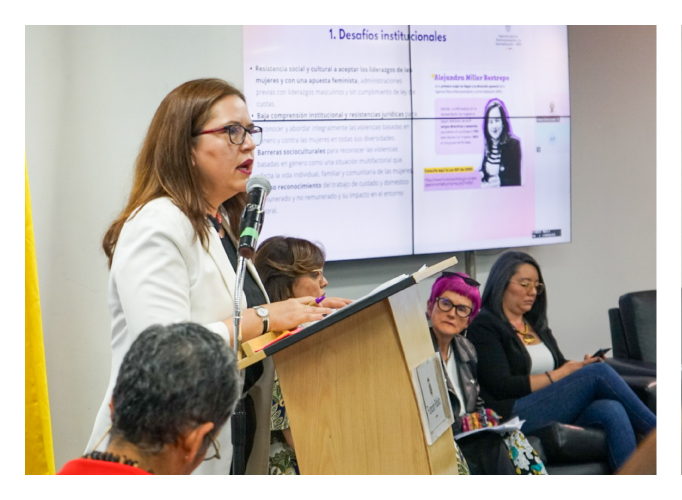 Un grupo de mujeres, una de ellas está en un atril hablando