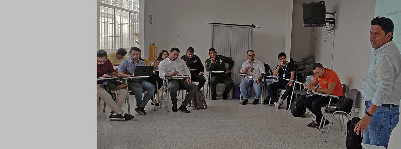 Foto de reunión de personas sentadas en pupitres en mesa redonda escuchando a un expositor
