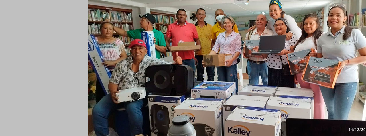 Foto de hombres y mujeres en una biblioteca mostrando productos de tecnología que recibieron