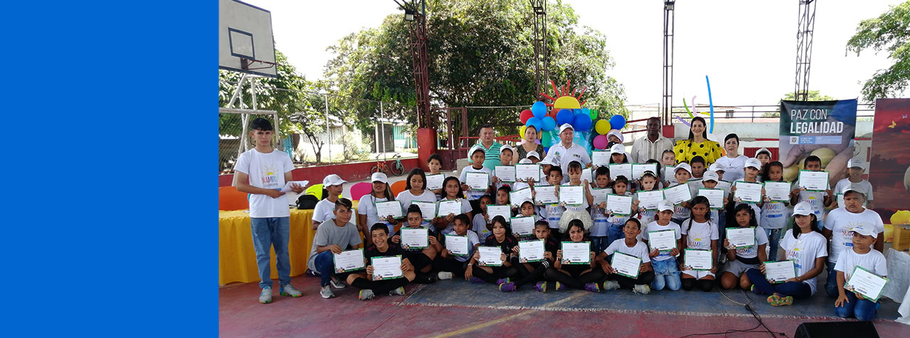 Grupo de niños  y niñas posando para una foto con su diploma en la mano en una cancha de baloncesto