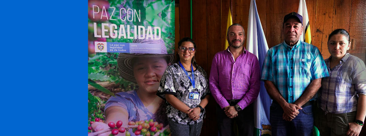 Foto de 4 personas de pie, entre ellos el director de la ARN - Andrés Felipe Stapper. Al lado derecho un pendón de la paz es con