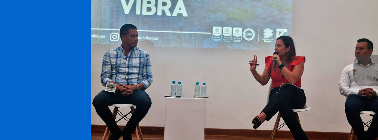 Panel con 3 expositores y de fonde se ve una proyección la pared de la esposición