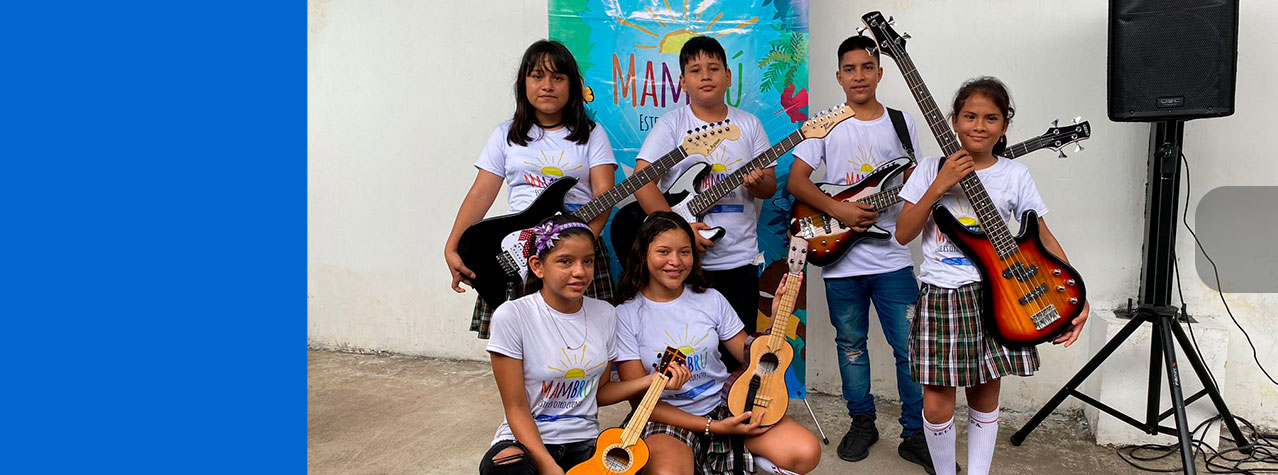 foto de 6 niñas y niños con instrumentos musicales de cuerda, guitarras, bajo, cuatro, Ukulele, de fondo pendón de la estrategia