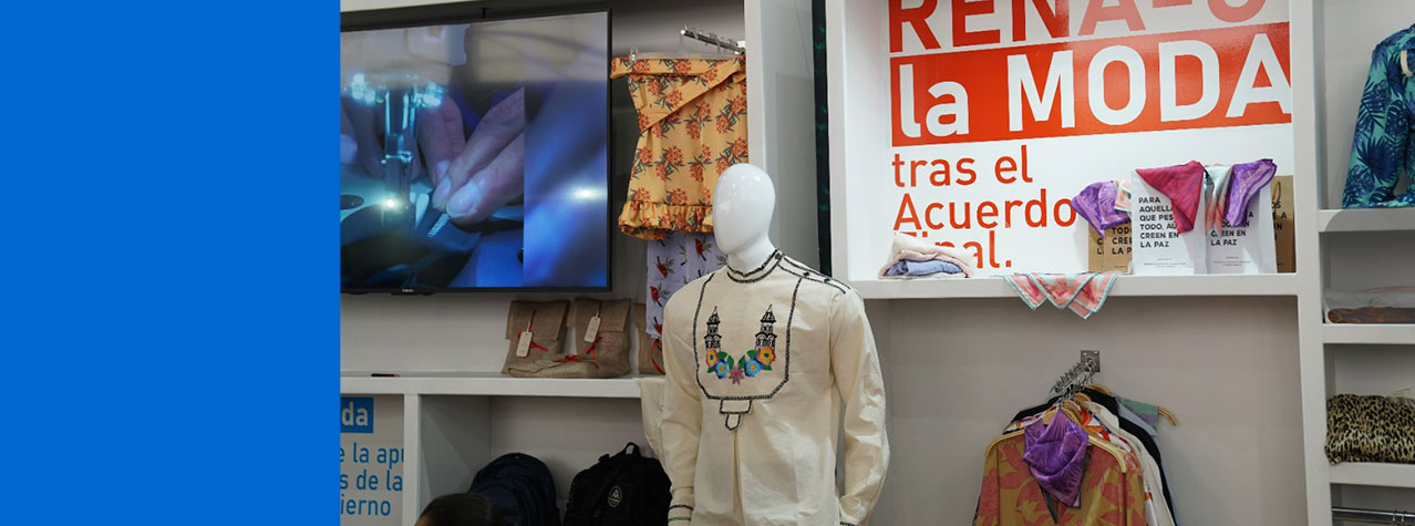 Foto del Stand de Rena-c la moda donde se pueden ver algunos de susproductos, camisa tejjida pañoletas y bolsos