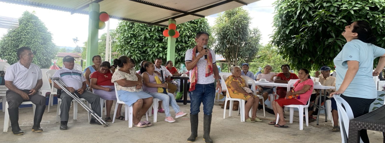Grupo de personas reunidas, un hombre hablando con un micrófono