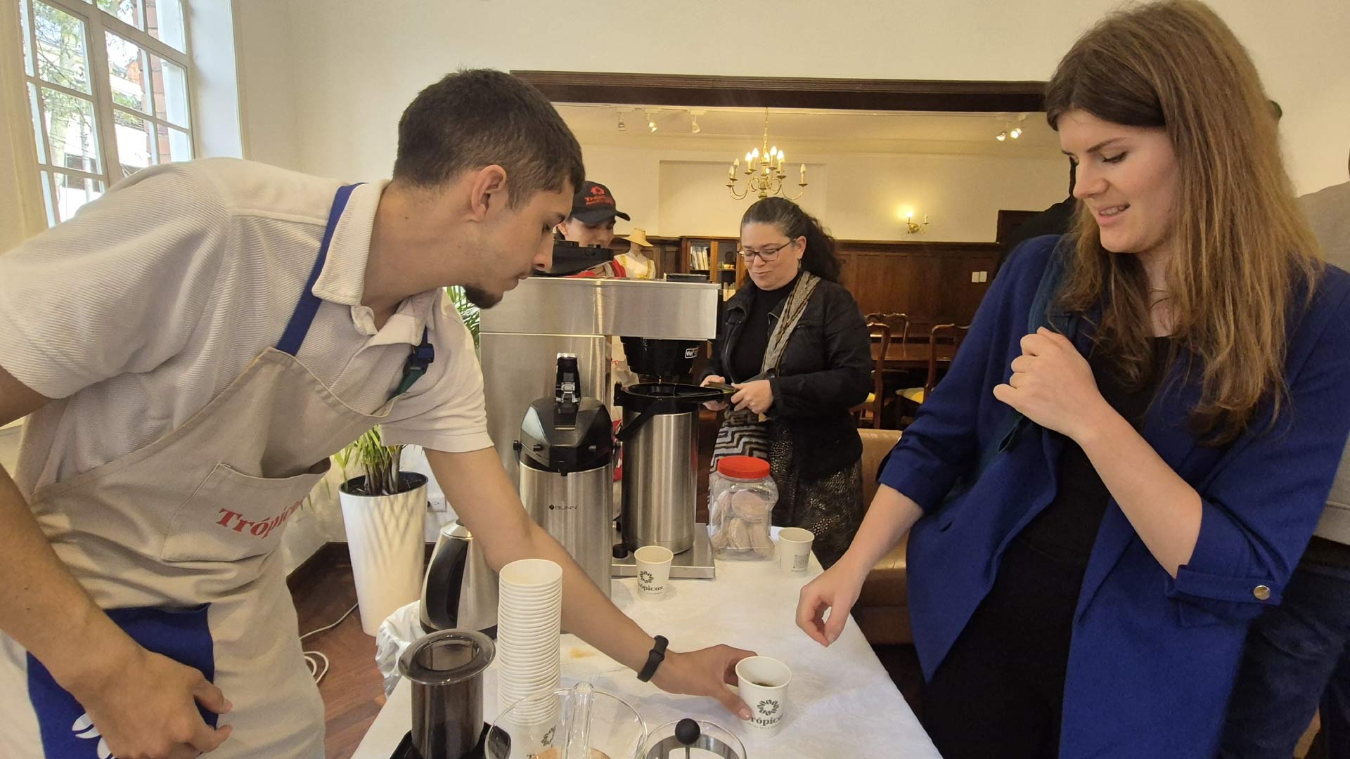 Joven entregando taza de café a representante internacional