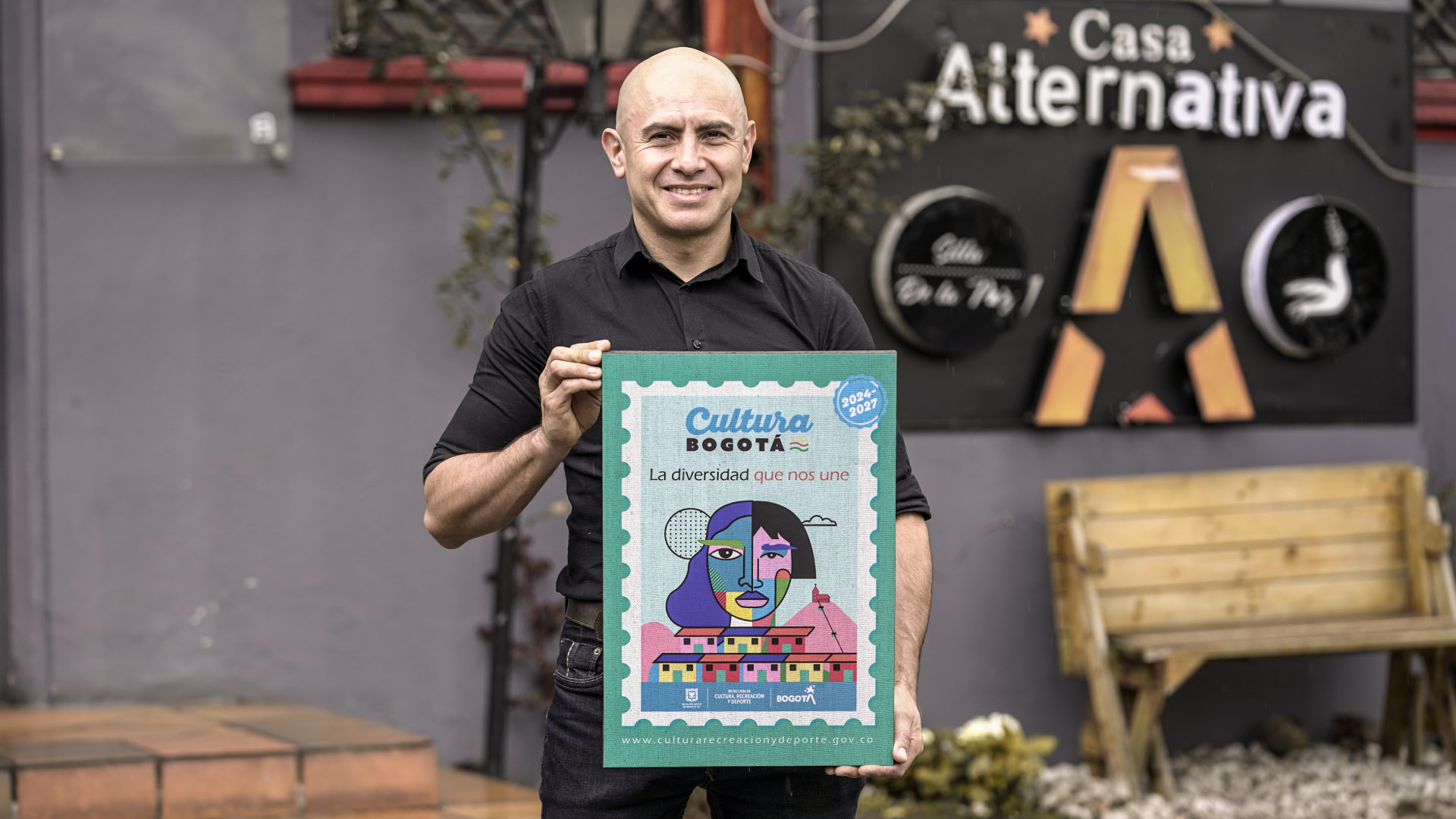 hombre posando con un cartel de cultura Bogotá
