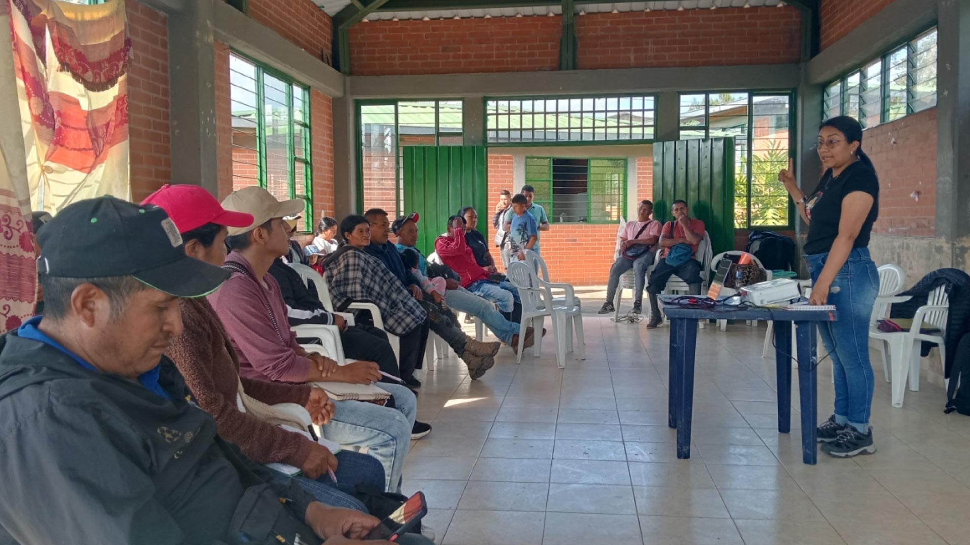 personas en salon comunal recibiendo charla