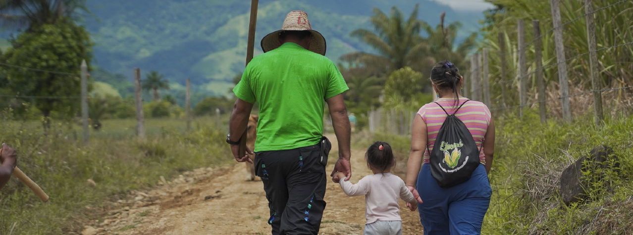 Dos adultos y una niña caminando por un sendero
