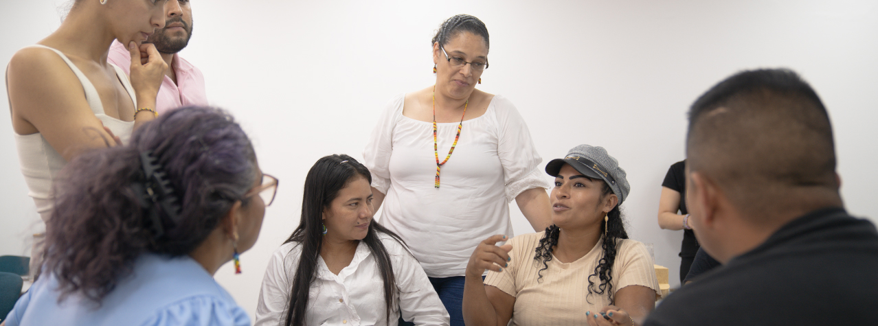 Grupo de personas reunidas, una de ellas hablando.