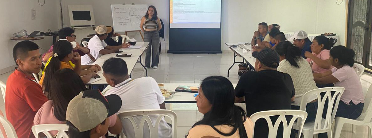 Grupo de personas reunidas, una persona al frente poniendo atención a lo que dicen los otros