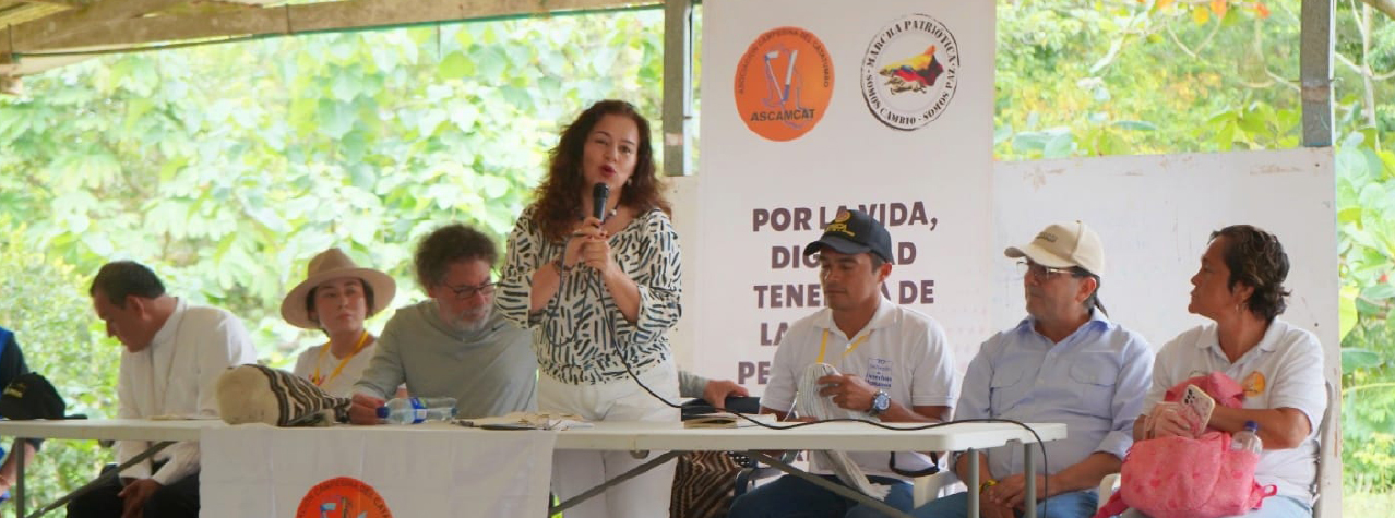 Grupo de personas en una mesa, una de ellas está hablando por micrófono