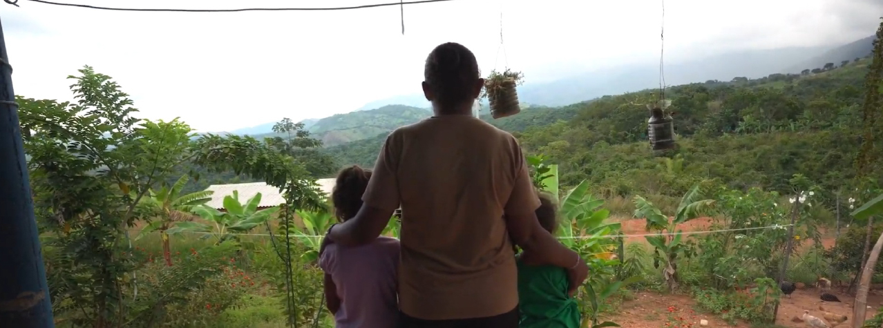Tres personas de espalda, dos niños y una señora, viendo al horizonte montañas