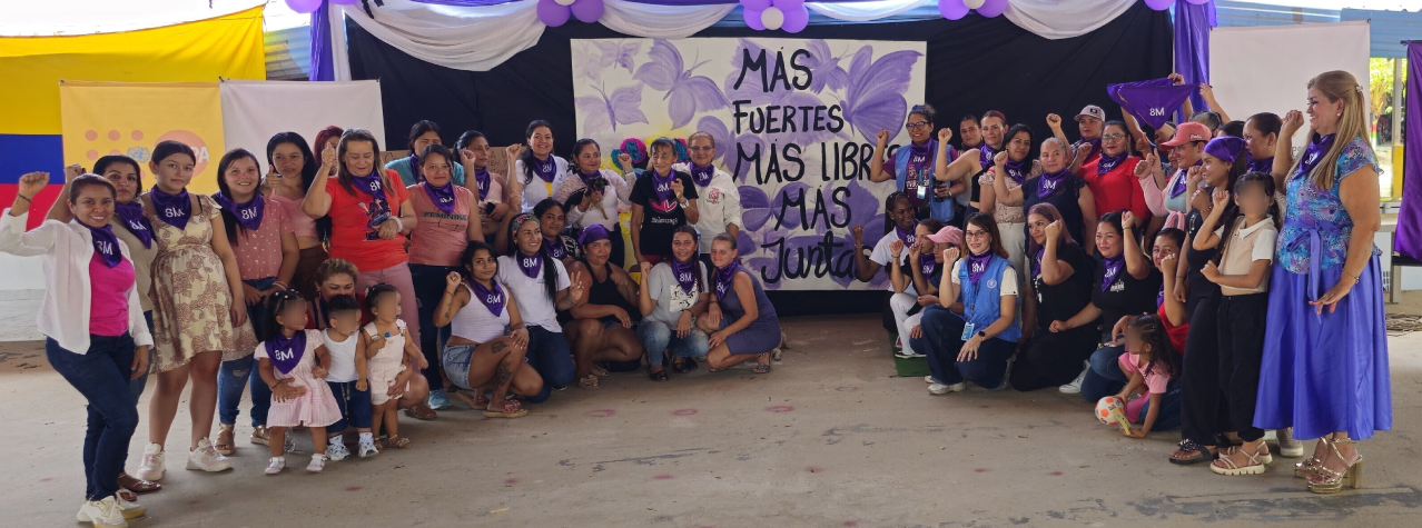 Grupo de mujeres reunidas en pose para foto con un cartel que dice Mas fuertes, mas libres, mas juntas