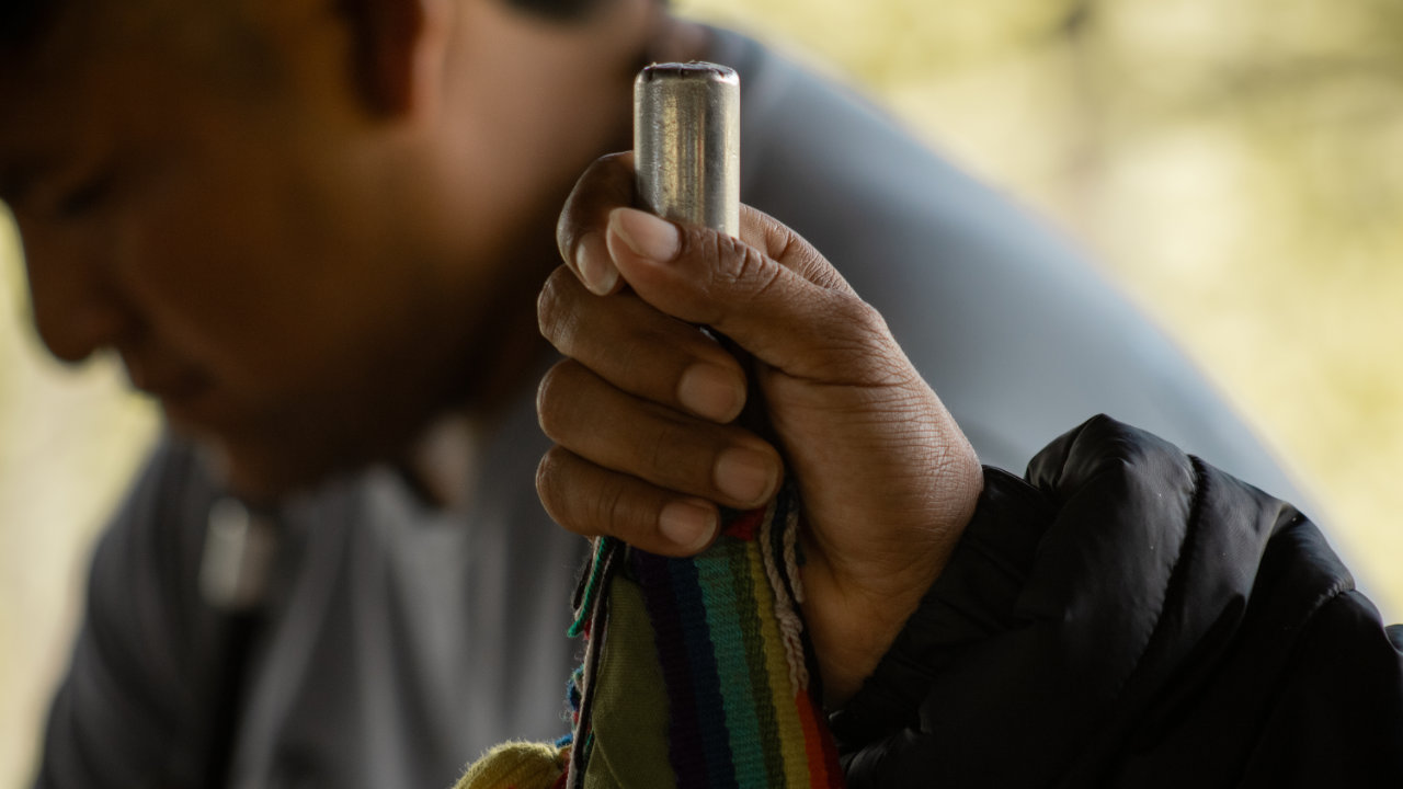 Primer plano de una mano sosteniendo una pieza artesanal tejida con franjas de colores durante una actividad comunitaria.