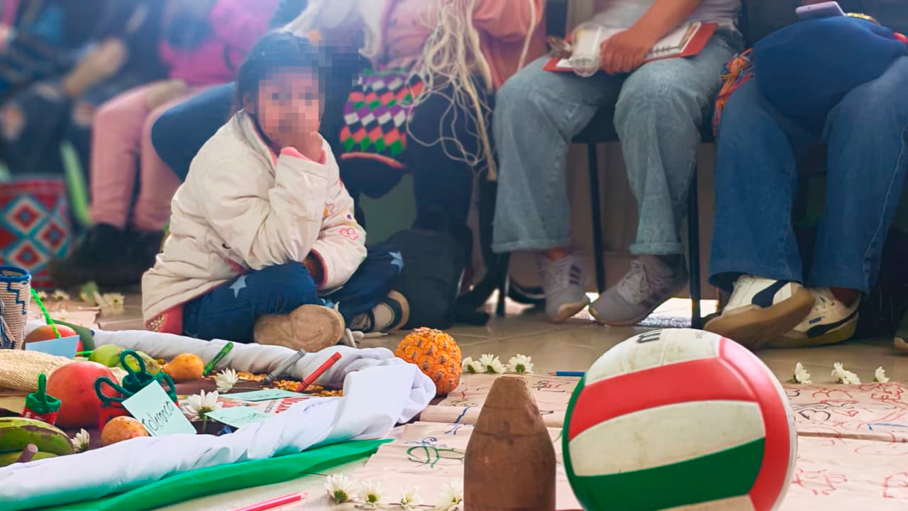 Niña participando en actividad comunitaria con materiales educativos durante jornada de prevención del reclutamiento de niños