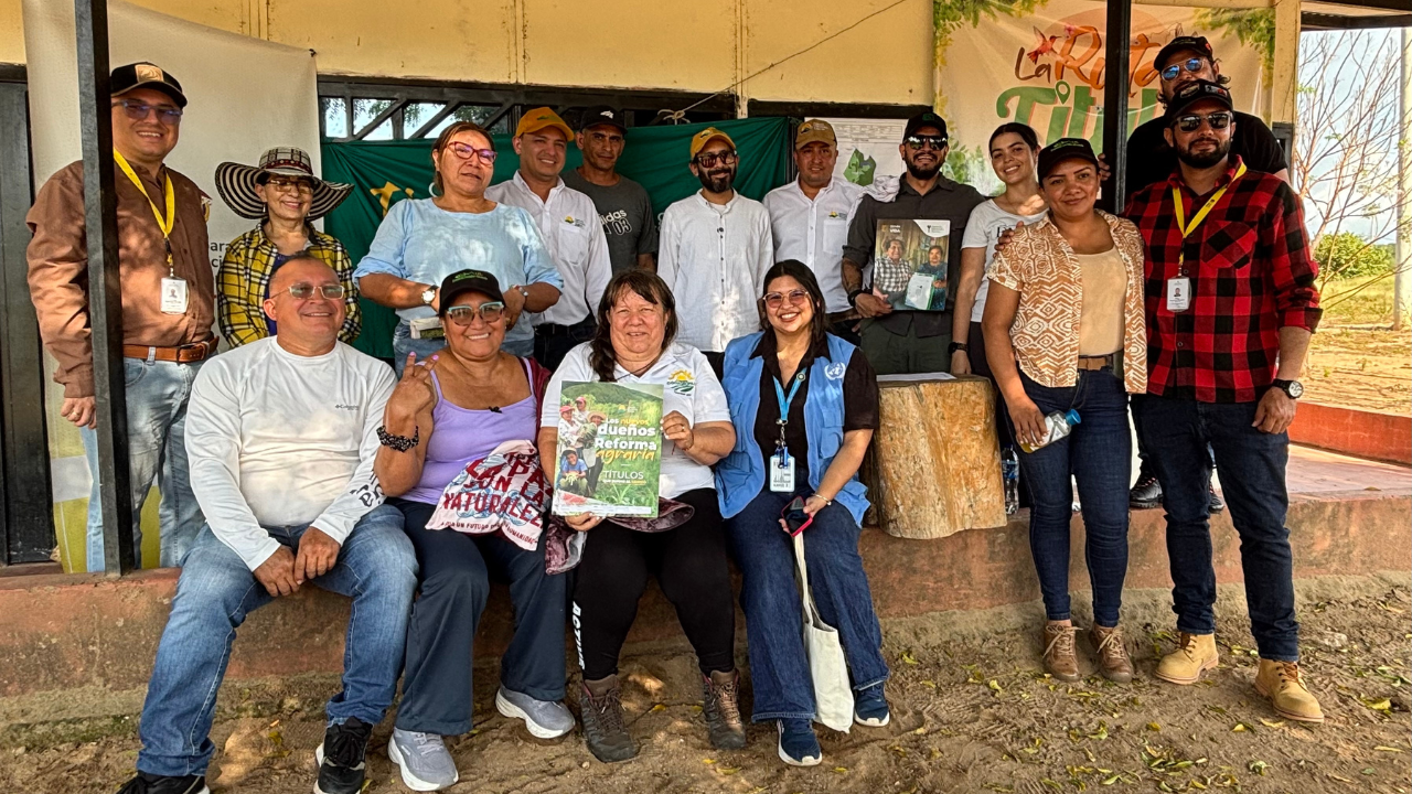 Grupo de personas en una zona rural participando en un evento de entrega de títulos de reforma agraria