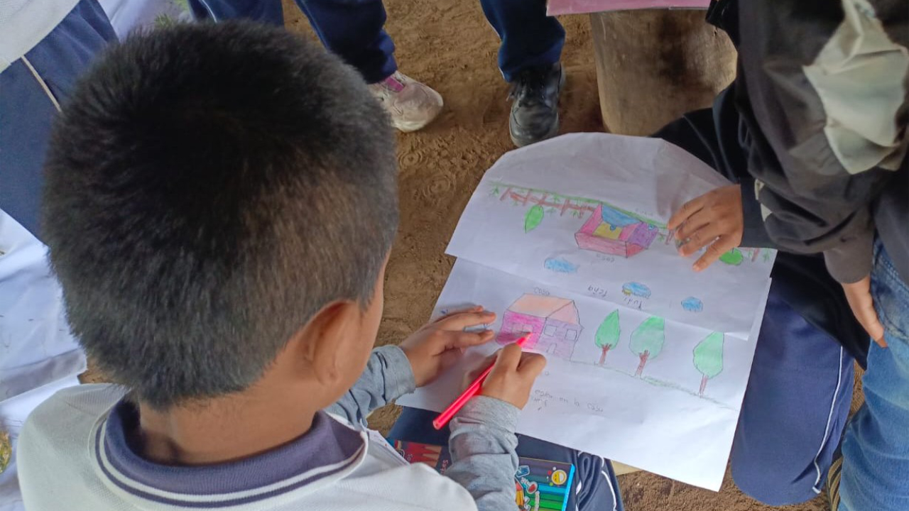 Niño dibujando en un papel con lápices de colores, mostrando creatividad y concentración en su actividad artística.