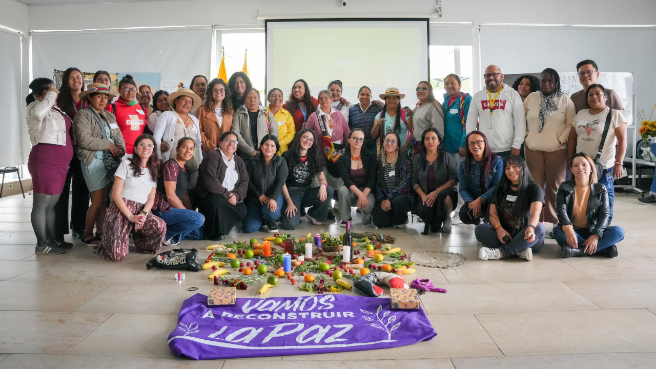 Grupo de participantes posa durante un encuentro alrededor de una composición con alimentos, velas y elementos simbólicos